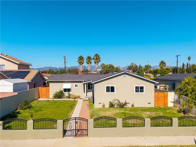 a view of a white house with a big yard and potted plants