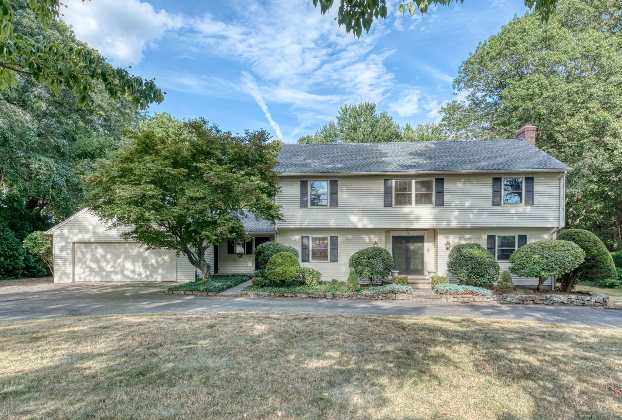 a view of a white house next to a yard with plants and trees