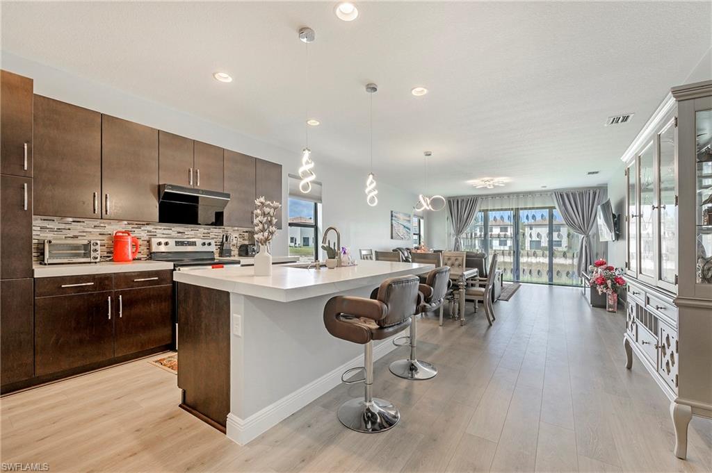a kitchen with stainless steel appliances kitchen island granite countertop a sink counter space and living room view