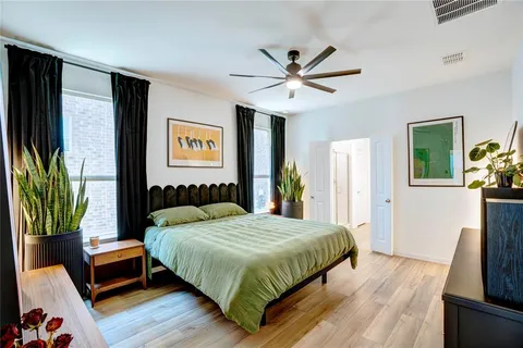 a bedroom with a bed a dresser with wooden floor