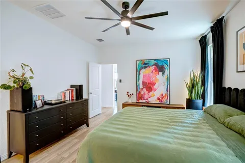 a bedroom with a bed painting on the wall and a potted plant