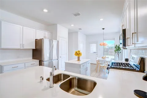 a kitchen with stainless steel appliances a sink a stove a refrigerator a counter top space and cabinets