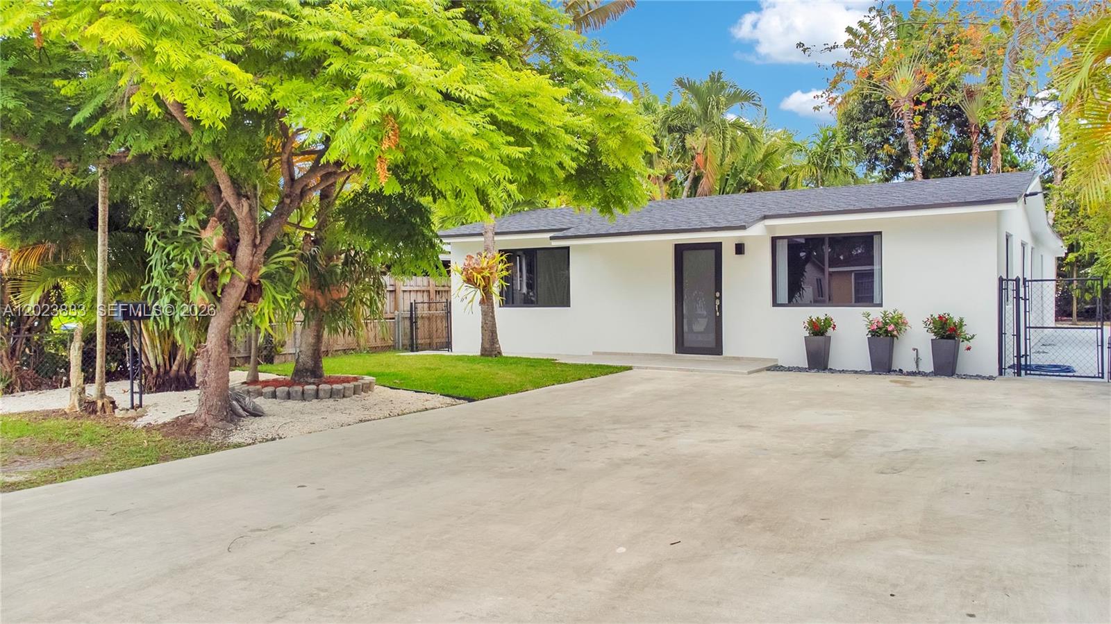 front view of house with a yard and trees all around