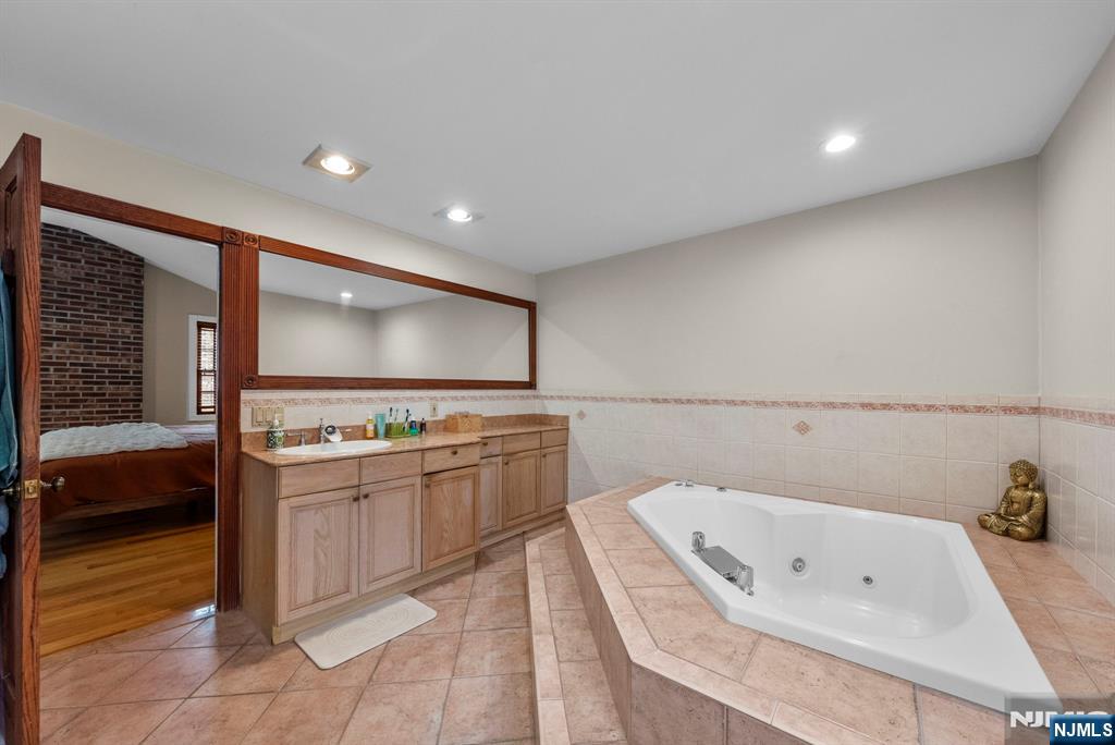 127 Hillside Avenue Cresskill, NJ 07626 - Photo 33 of 42 a bathroom with a tub a sink and a large mirror