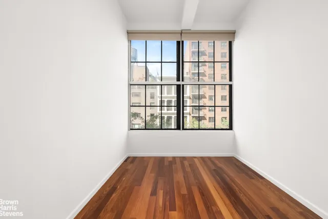 a view of a hallway with wooden floor and a bathroom