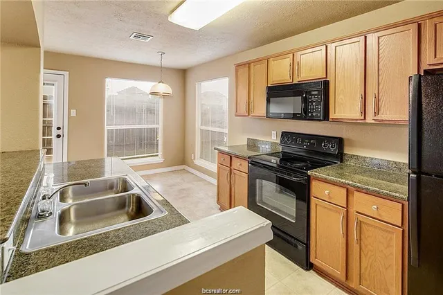 a kitchen that has a sink wooden cabinets and a granite counter top