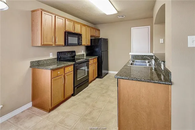a kitchen with granite countertop a stove top oven a sink a counter space and cabinets