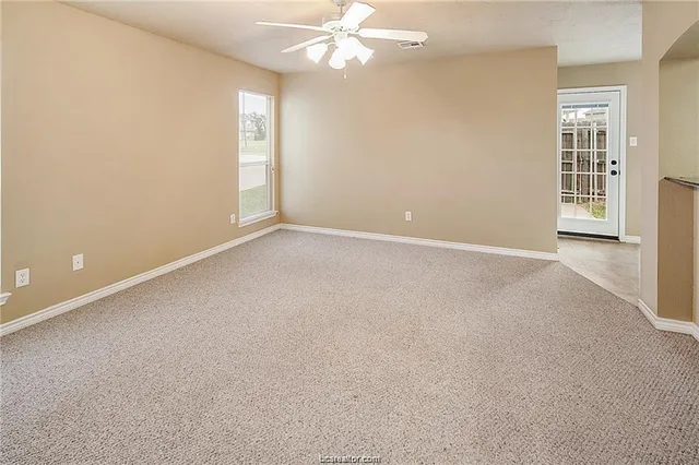 an empty room with windows and fan