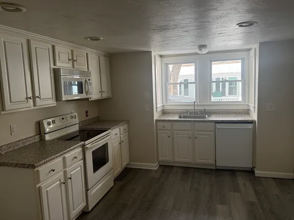 a kitchen with granite countertop white cabinets and white appliances