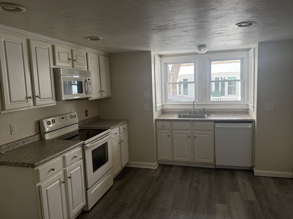 6 Ninth Street, Unit 1 Wareham, MA 02558 - Photo 13 of 15 a kitchen with granite countertop white cabinets and white appliances