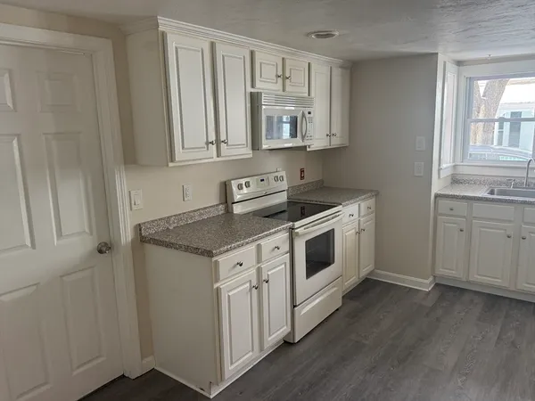 a view of a kitchen with sink microwave and cabinets
