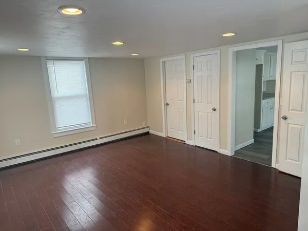 an empty room with wooden floor and windows with curtains