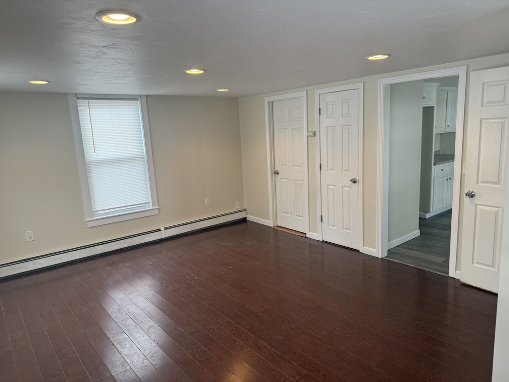 6 Ninth Street, Unit 1 Wareham, MA 02558 - Photo 5 of 15 an empty room with wooden floor and windows with curtains