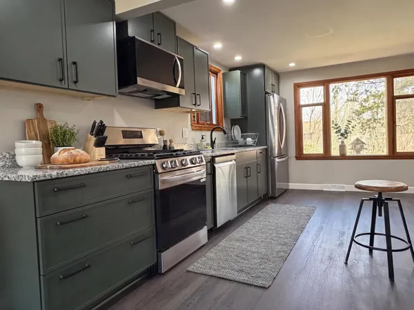 a kitchen with stainless steel appliances granite countertop wooden floors and sink