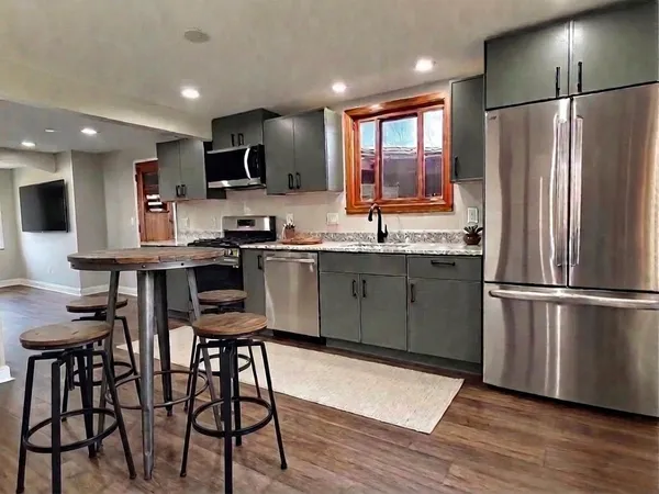 a kitchen with stainless steel appliances granite countertop a refrigerator a sink a stove a dining table and chairs