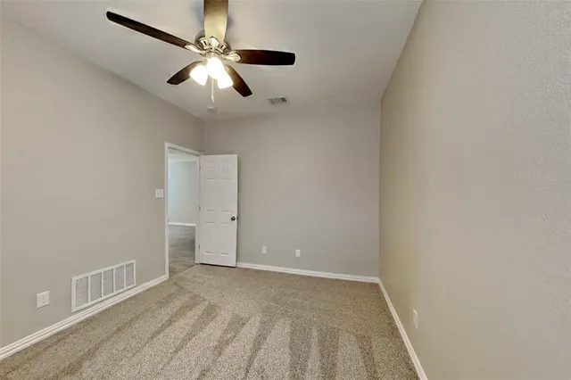 an empty room with a ceiling fan and carpet
