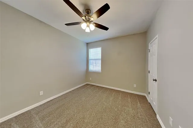 an empty room with a chandelier fan and windows