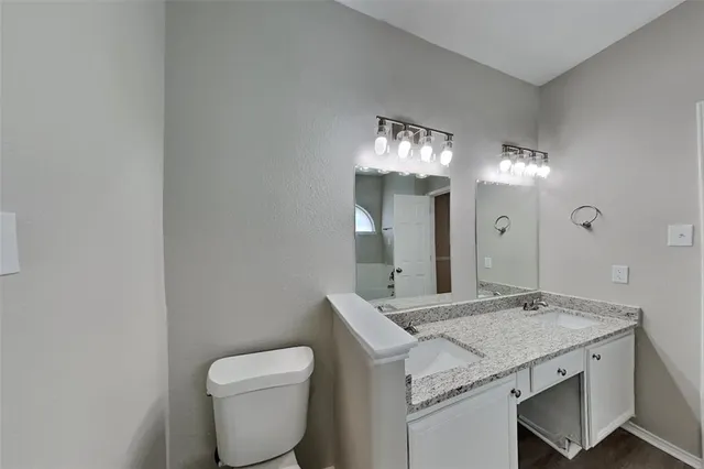 a bathroom with a granite countertop sink a toilet and a large mirror