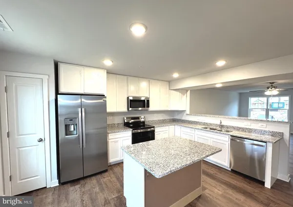 a kitchen with stainless steel appliances kitchen island granite countertop a stove a sink and a microwave
