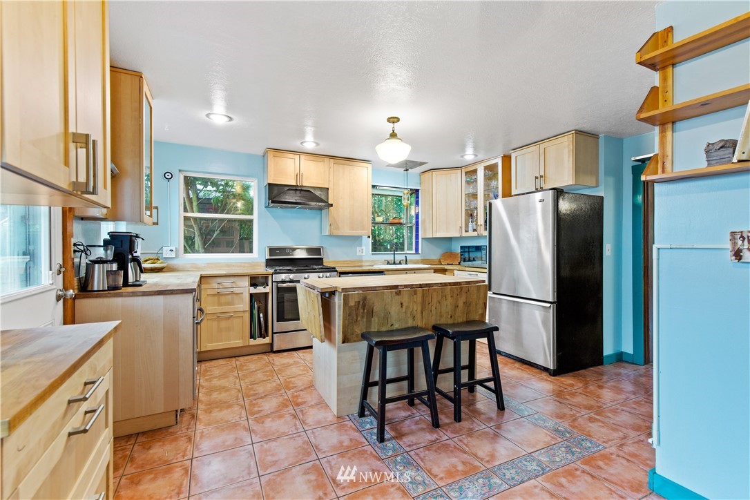 907 North 68th Street Seattle, WA 98103 - Photo 16 of 36 a kitchen with stainless steel appliances a refrigerator a stove a sink a dining table and chairs