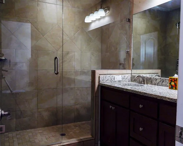 a bathroom with a granite countertop sink a mirror and shower