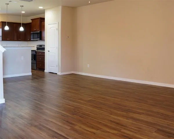 wooden floor in an empty room with a kitchen