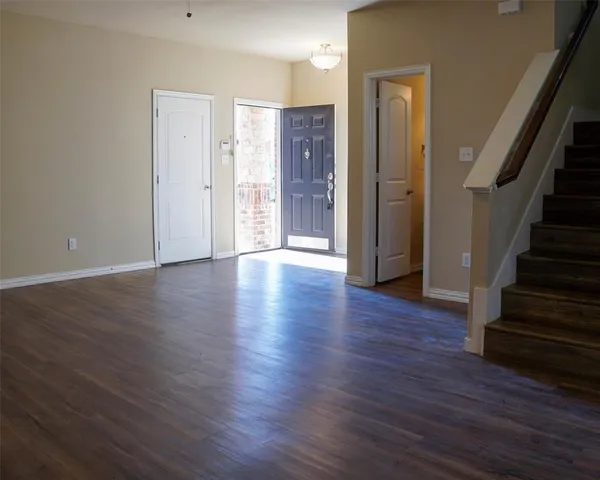 a view of an empty room with wooden floor and stairs