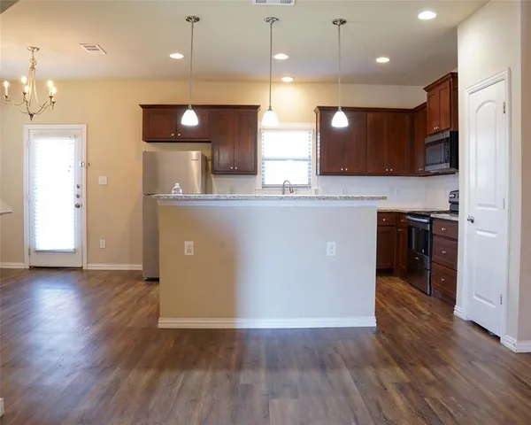 a view of kitchen with wooden floor and stainless steel appliances