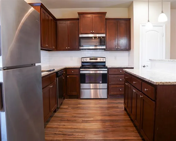 a kitchen with stainless steel appliances granite countertop a stove a sink and a refrigerator