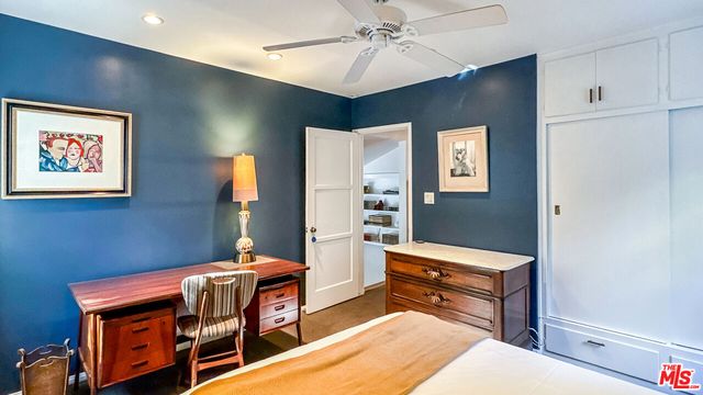 a room with chandelier fan and wooden furniture
