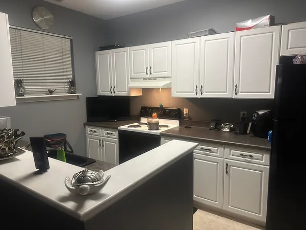 a kitchen with granite countertop a sink dishwasher stove and white cabinets