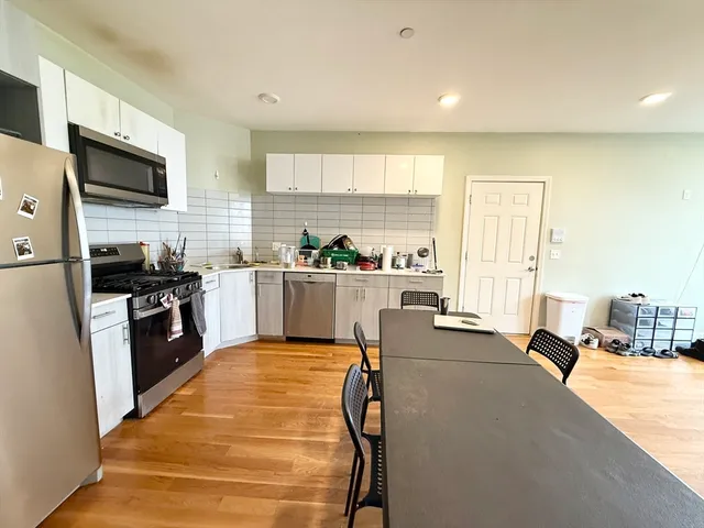 a large kitchen with kitchen island a large window cabinets and stainless steel appliances