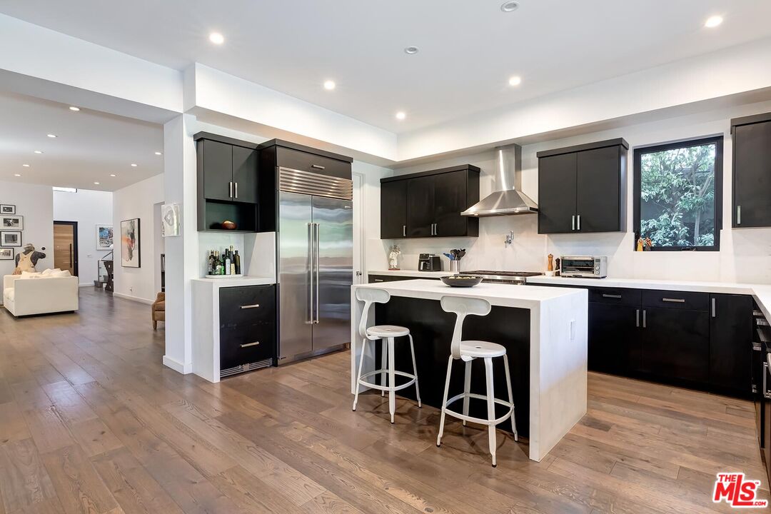 10521 Northvale Road Los Angeles, CA 90064 - Photo 22 of 52 a kitchen with stainless steel appliances granite countertop a stove top oven a sink dishwasher a refrigerator and a dining table with wooden floor