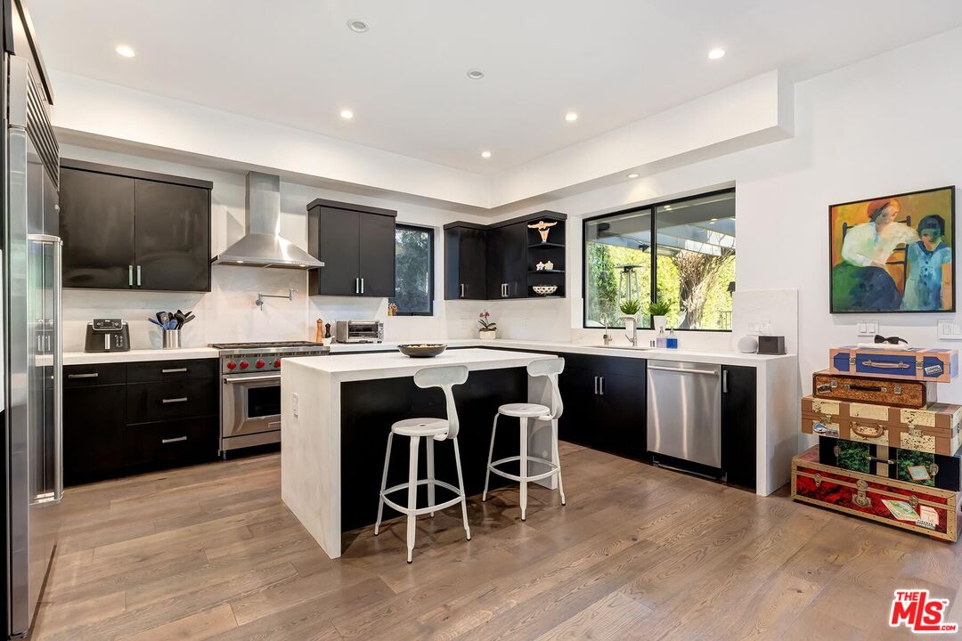 10521 Northvale Road Los Angeles, CA 90064 - Photo 23 of 52 a kitchen with stainless steel appliances granite countertop a stove top oven a sink dishwasher a refrigerator and a dining table with wooden floor