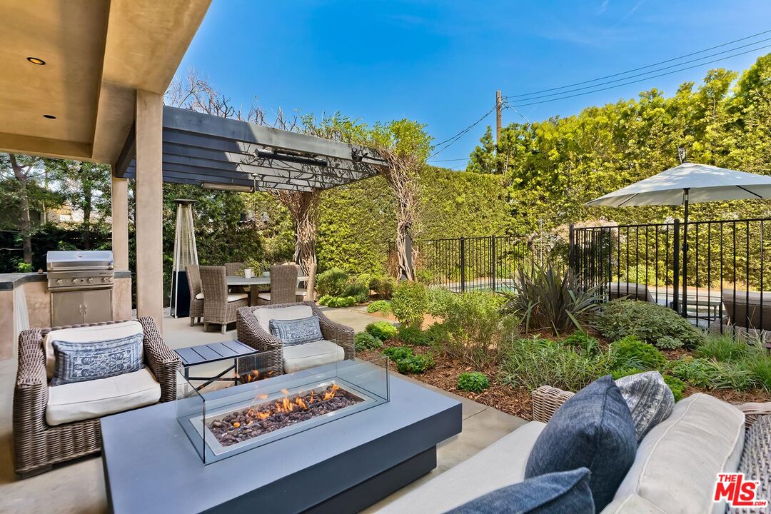 10521 Northvale Road Los Angeles, CA 90064 - Photo 5 of 52 a view of a patio with couches table and chairs under an umbrella with a fire pit