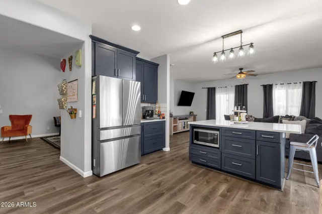 a kitchen with stainless steel appliances granite countertop a refrigerator a stove a sink dishwasher a refrigerator and a dining table with wooden floor