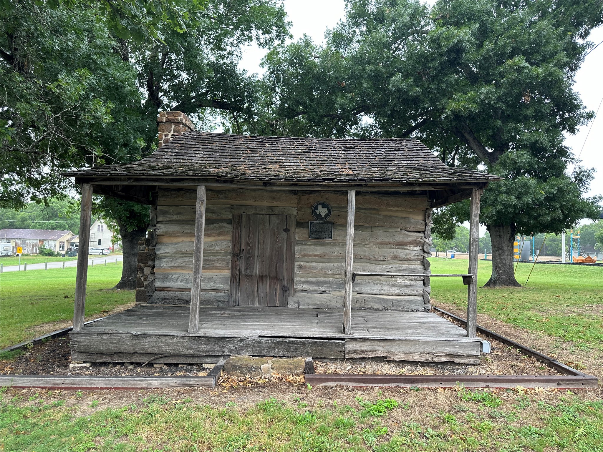 608 Lamar Street Luling, TX 78648 - Photo 7 of 7 Rustic log cabin structure featuring a stone chimney and a weathered wood-shingle roof