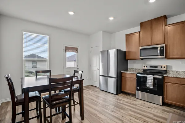 a kitchen with stainless steel appliances a dining table chairs stove refrigerator and microwave