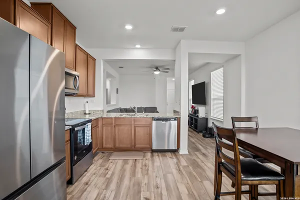 a open kitchen with stainless steel appliances granite countertop a refrigerator a stove top oven a sink dishwasher and white cabinets with wooden floor