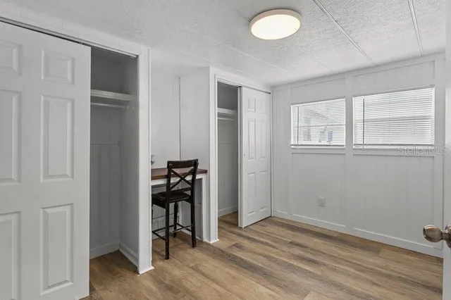 an empty room with wooden floor closet and windows