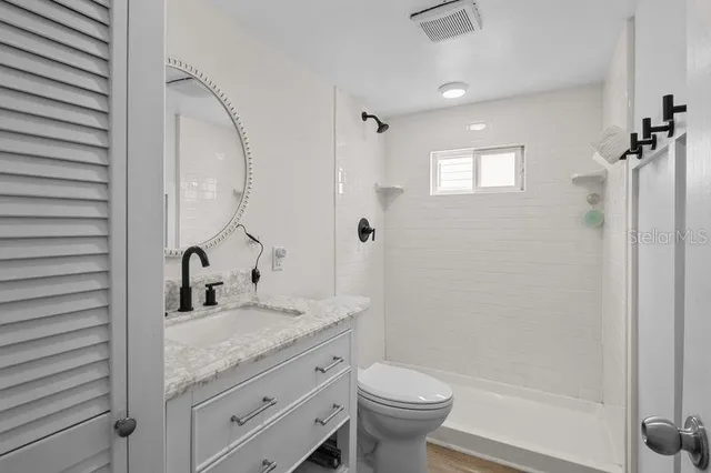 a bathroom with a granite countertop sink toilet and shower