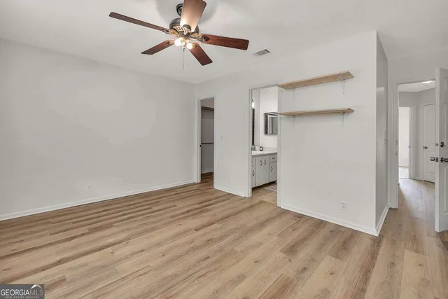 a view of empty room with wooden floor and ceiling fan