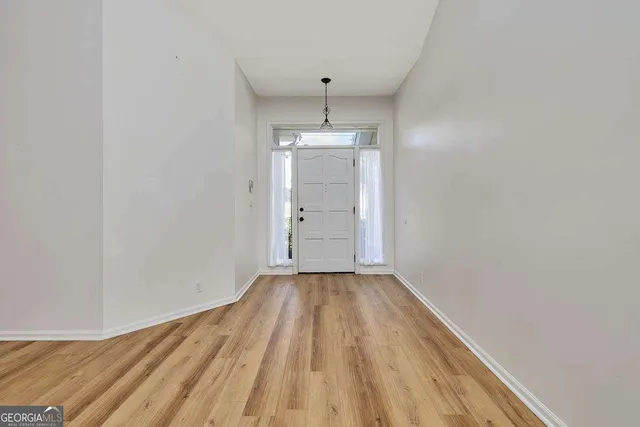 a view of an empty room with wooden floor and window