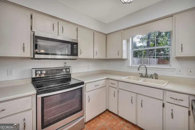 a kitchen with cabinets stainless steel appliances a sink and a window