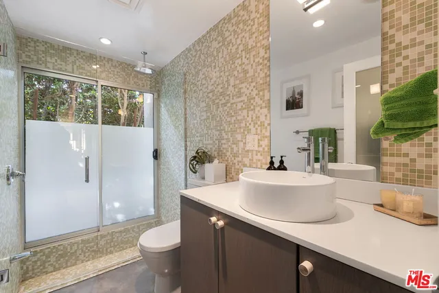 a bathroom with a sink a toilet a mirror and shower