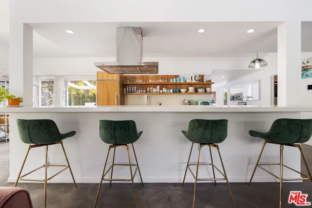 a kitchen with stainless steel appliances a dining table chairs and a living room view