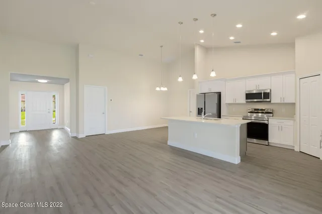 a large kitchen with a wooden floor and stainless steel appliances