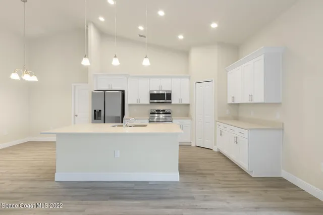 a view of an empty room with kitchen and kitchen view