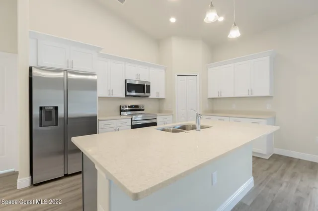 a view of kitchen with sink and refrigerator
