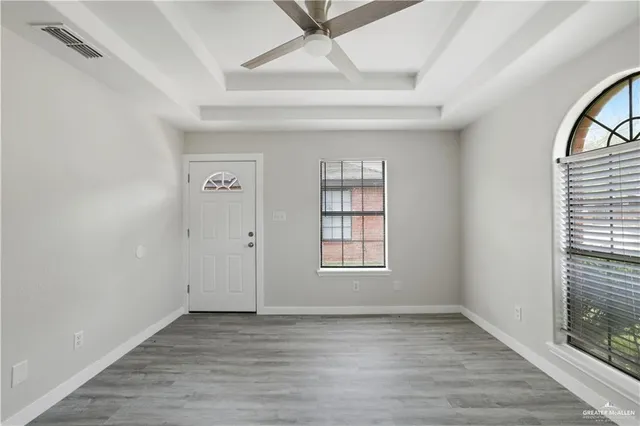 an empty room with wooden floor and windows